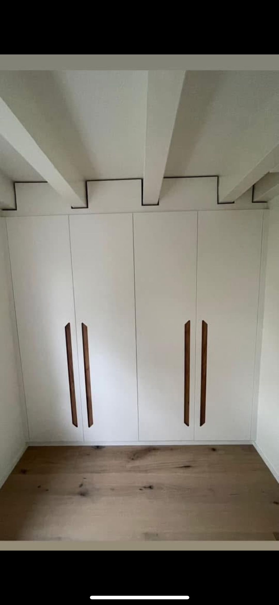 Armoire sur mesure avec poignées bois sous poutres apparentes, dressing Le Vaud