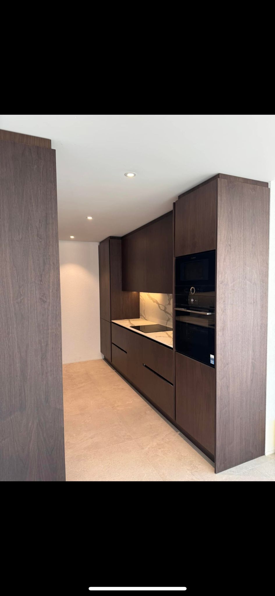 Cuisine en bois foncé avec crédence marbre et électroménager encastré, pose cuisine Suisse